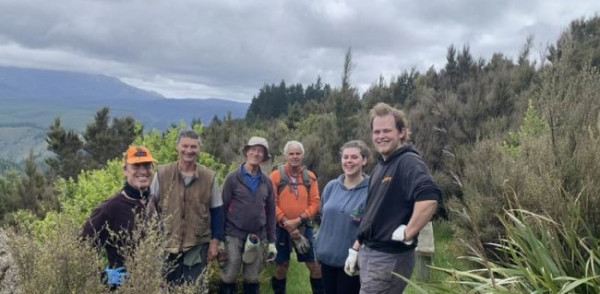 Photo of group on hill surrounded by native bush and wilding conifers